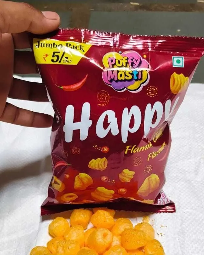 Happy ₹5 packet from Puffy Masti, held in hand with the snack tipped out below